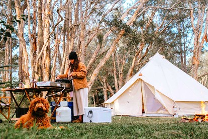 A happy glamper cooks outside her bell tent in Glenworth Valley, New South Wales, Australia