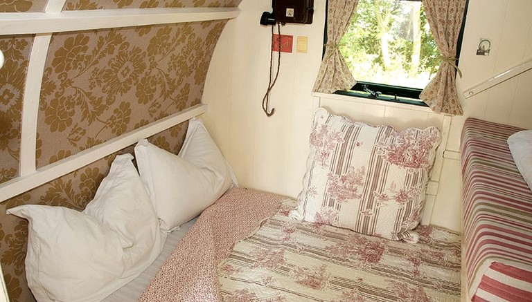 Bed in a gypsy caravan holiday rental in the French countryside.