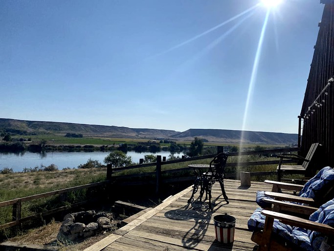 RV overlooking a river, with attached barn and decking for relaxing vacation.