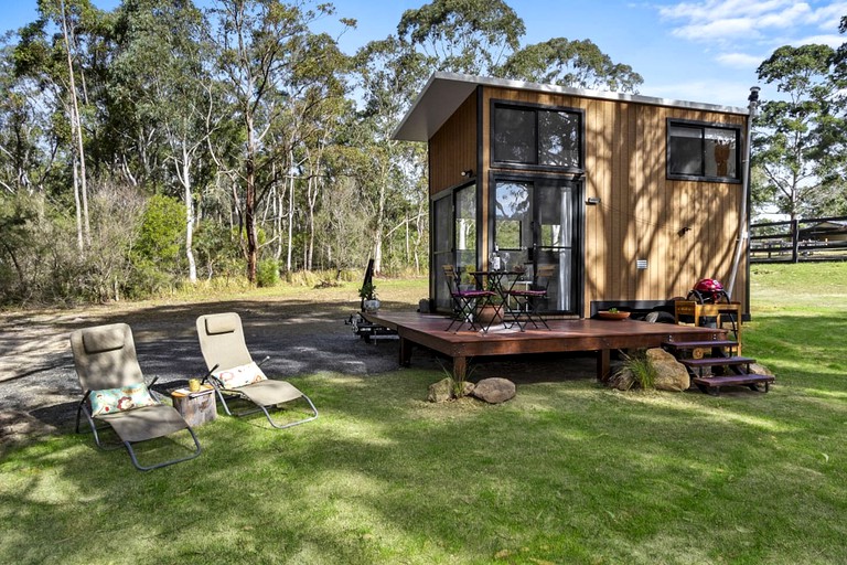 This unique Kangaroo Valley accommodation on its raised deck with outdoor furniture on the lawn in front of it