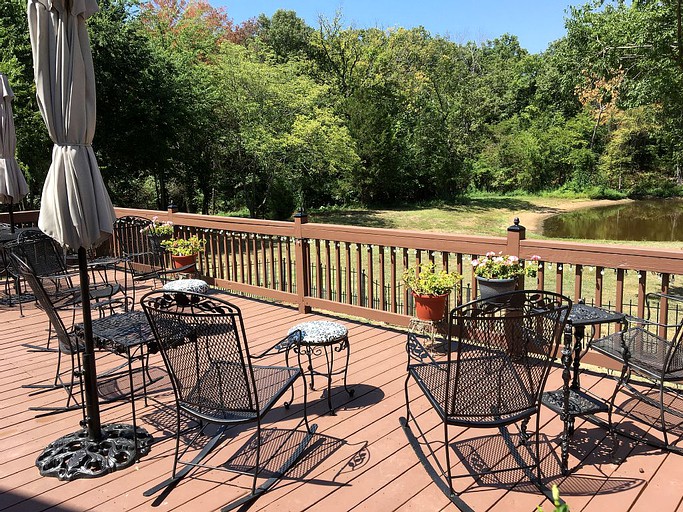 Private deck with patio furniture overlooking backyard with small pond in Texas.