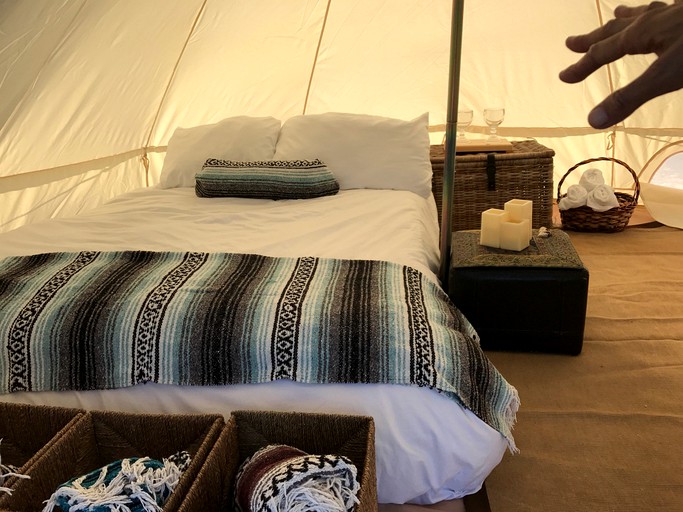 Go camping! San Felipe luxury tent interior with double bed and hand sneaking into the frame