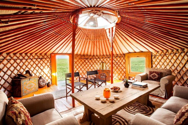 Mongolian tent furnished with double bed and a living area.