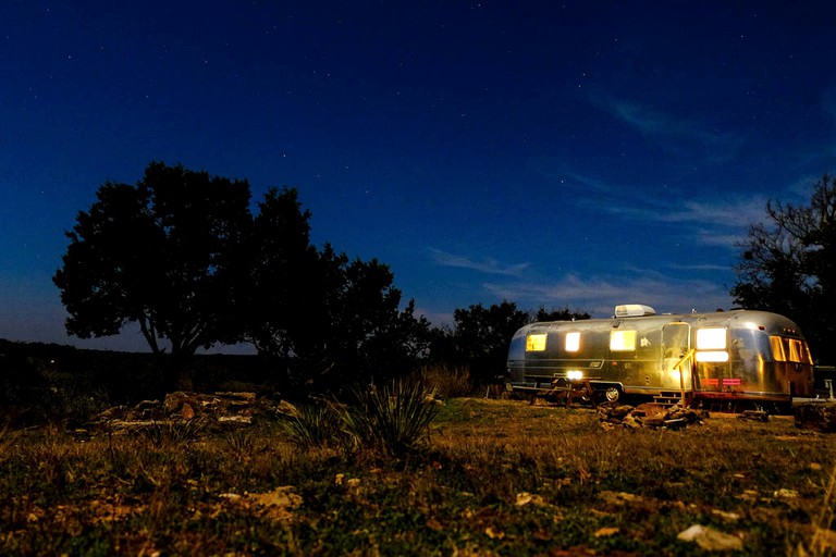 Airstream illuminated at night in an open clearing in Fredericksburg, Texas.