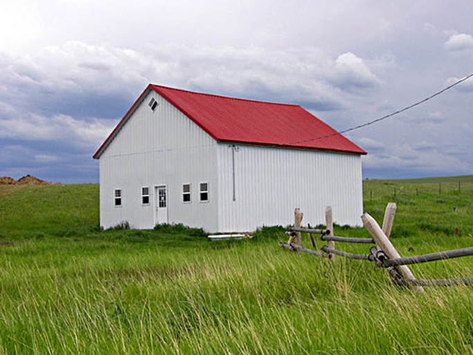 White cottage in a field of grass in Montana.