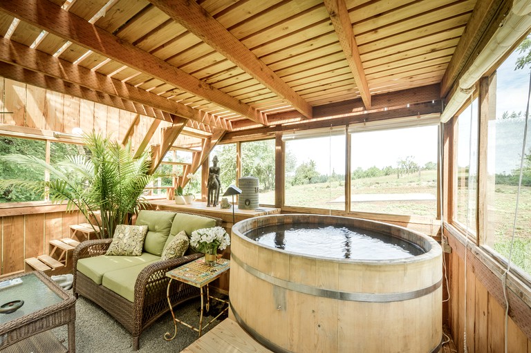 Private hot tub with views of surrounding fields of cottage rental in Oregon. Wooden beams for cottage getaway: Portland vacations await