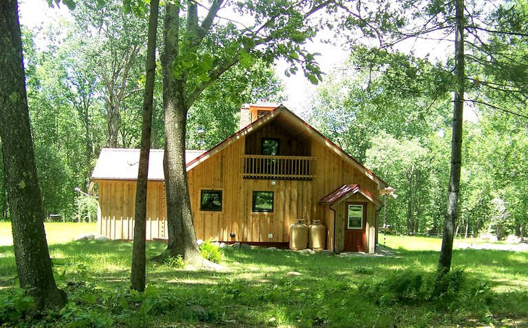 Side view of a log cabin rental surrounded by trees in Massachusetts.